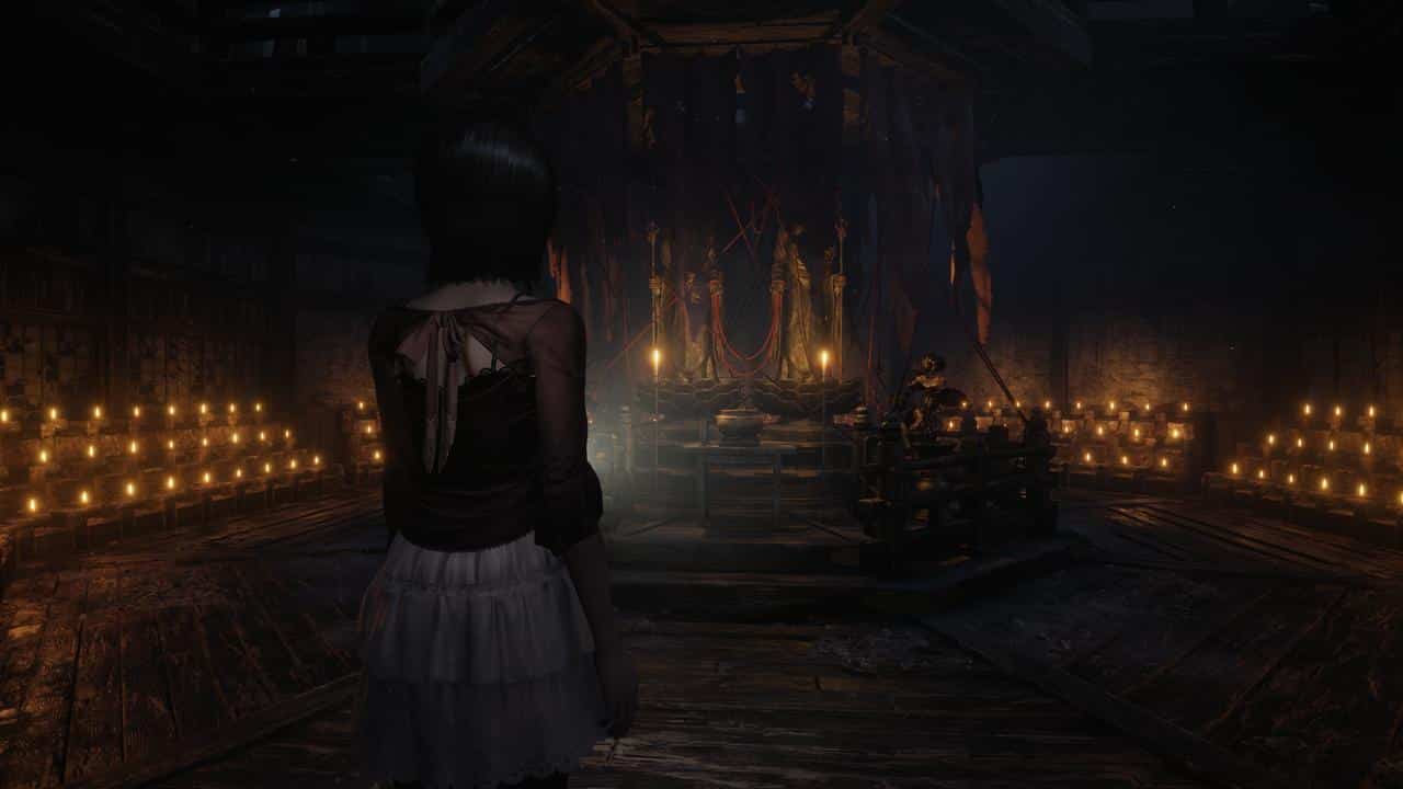 A girl stands in a dark room filled with lit candles, facing a mysterious altar with hanging figures—an eerie scene reminiscent of FATAL FRAME II: Crimson Butterfly REMAKE.