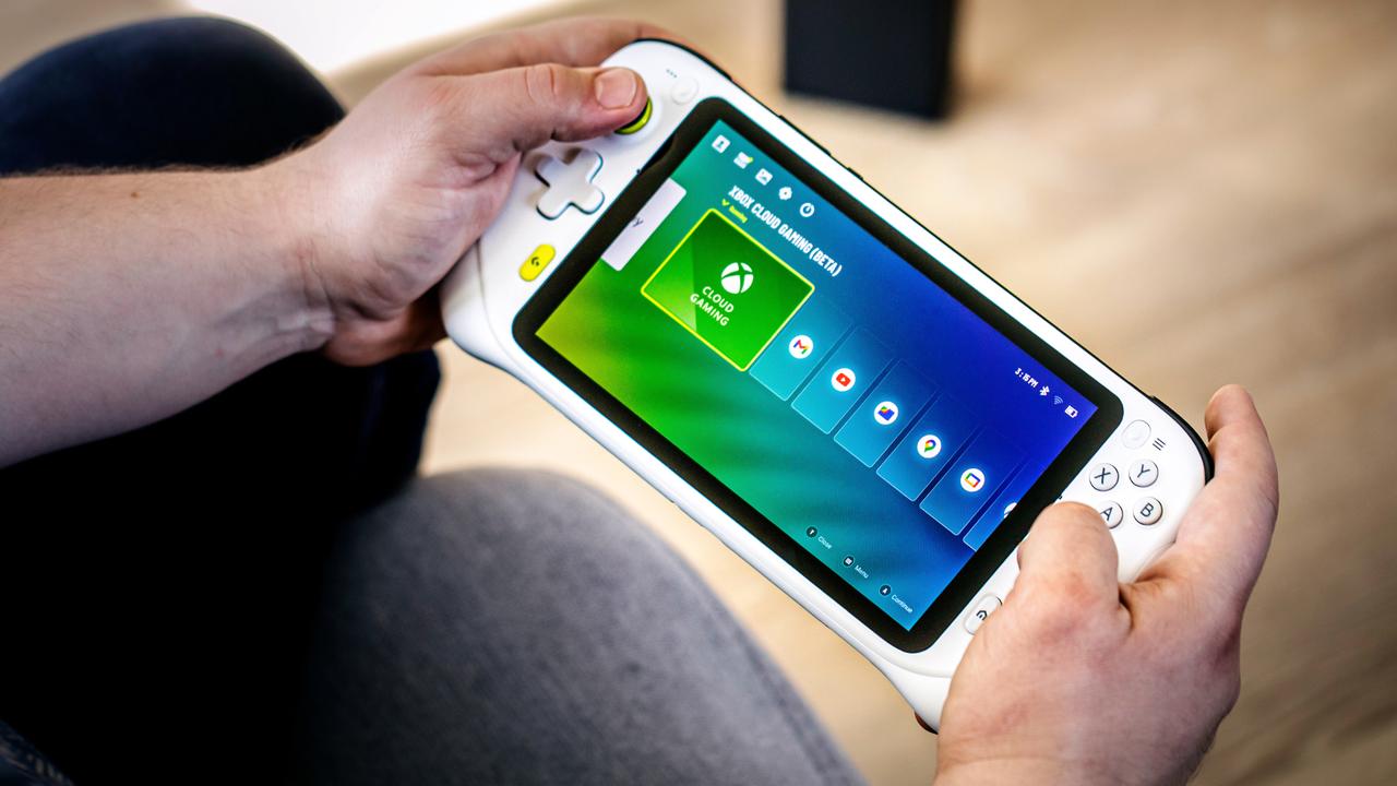 A person holding a white Logitech G Cloud handheld device displaying the Xbox Cloud Gaming interface on the screen.