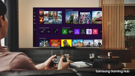 A person sitting on a couch using a wireless controller to browse the Samsung Gaming Hub on a smart TV, featuring icons for Xbox, NVIDIA GeForce NOW, and Amazon Luna.
