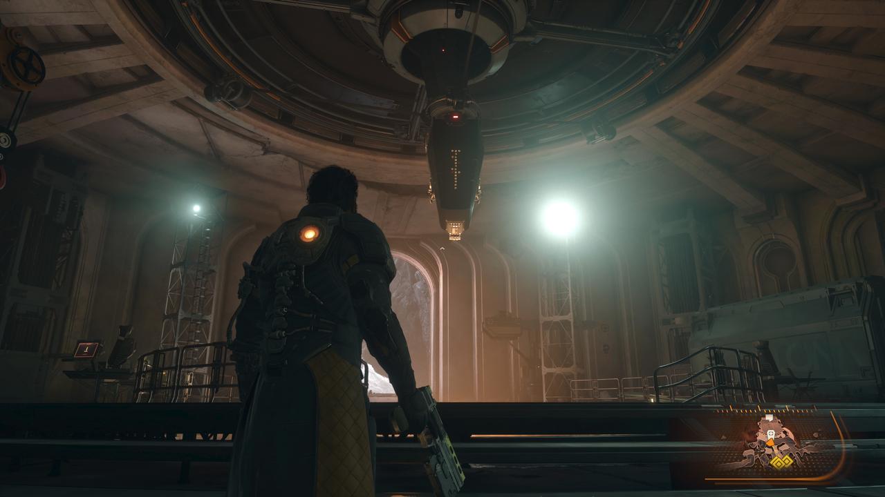 Arjun Devraj looks up at a massive, glowing mechanical structure inside a cavernous alien ruin on the planet Carcosa.