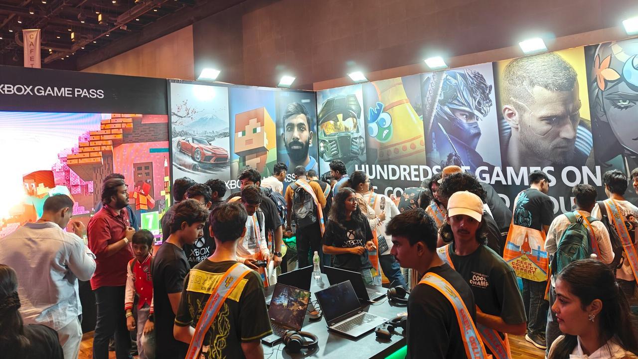 A crowded Xbox Game Pass booth at Mumbai Comic Con 2026 with fans using laptop demo stations under a mural promoting cloud gaming accessibility.