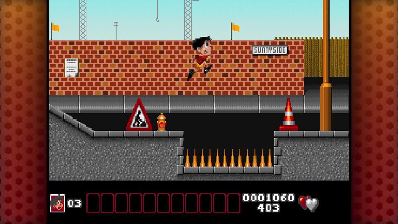 Soccer Kid jumps over a spike pit between platforms in Soccer Kid Collection.