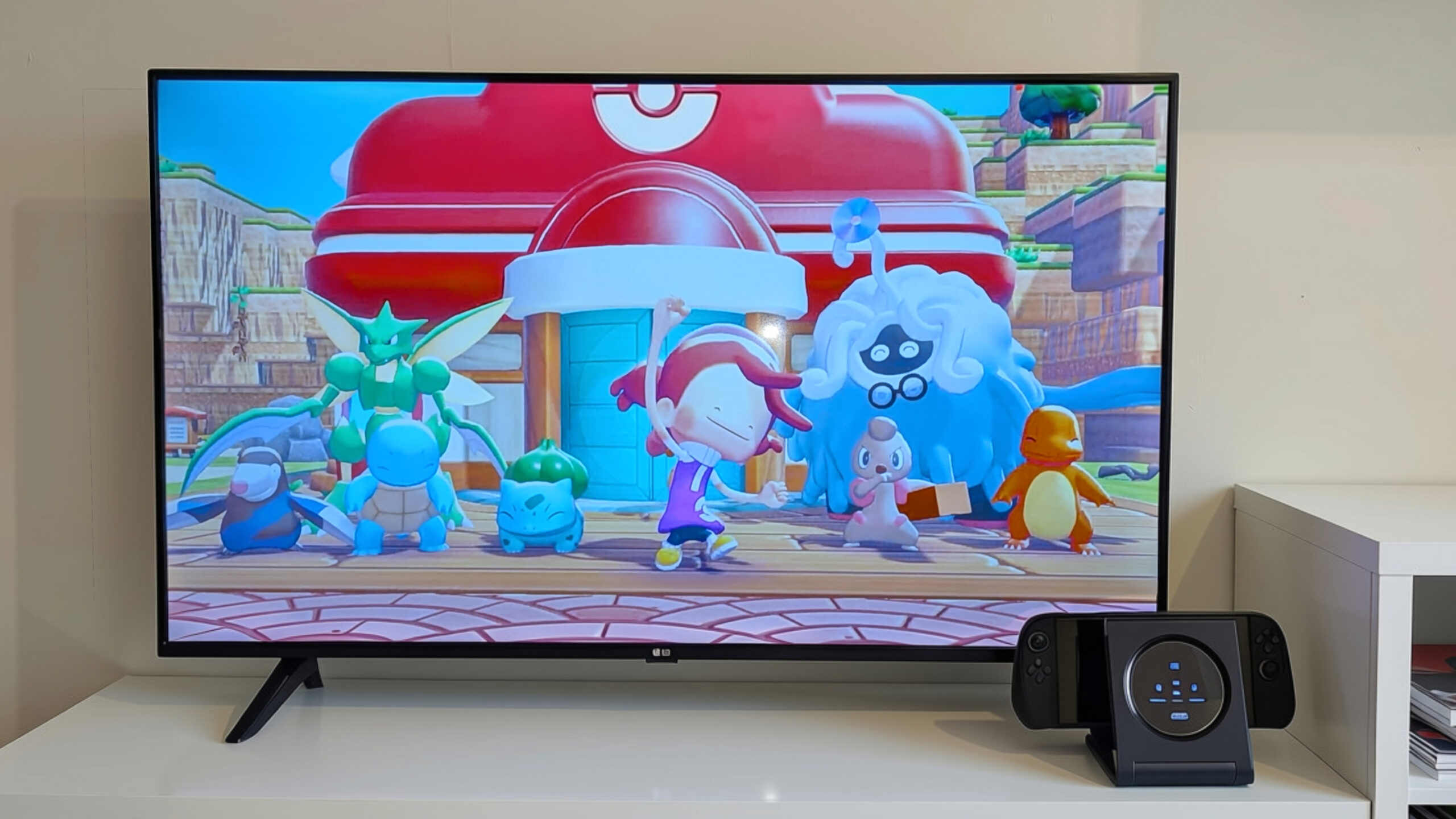 Disseny sense títol - 1 A TV screen showing animated characters from Pokémon standing in front of a Poké Center building