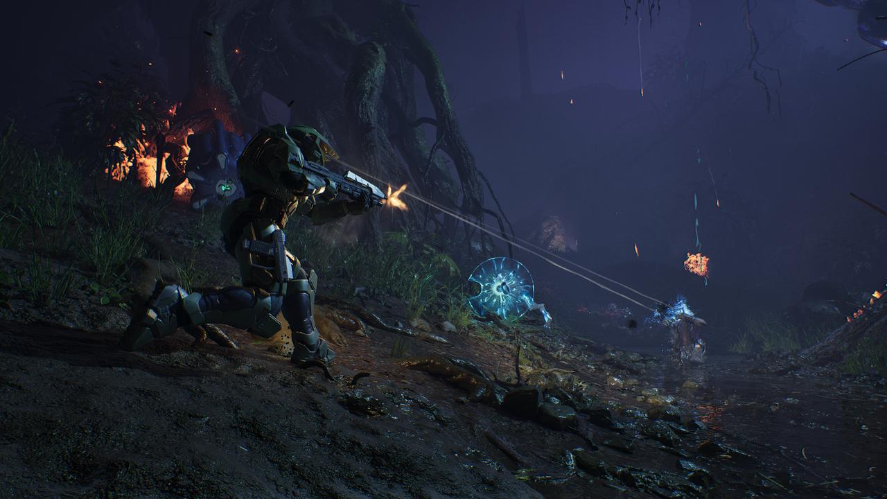 Master Chief fires at Flood enemies in a dark forest during Halo: Campaign Evolved.