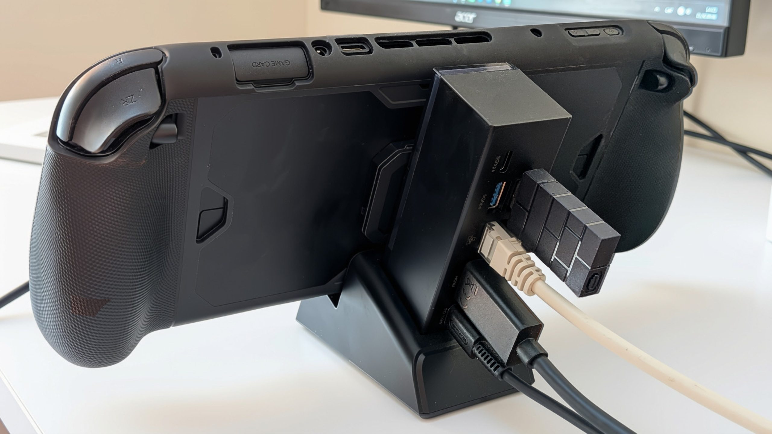 Disseny sense títol - 1 Black Gamecard handheld console connected to a monitor with HDMI and power cables