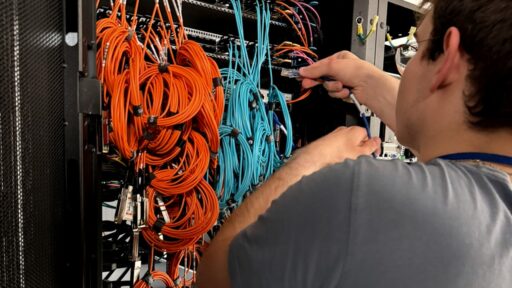 Technician connecting network cables inside a server rack for Boosteroid infrastructure at DC2SCALE.
