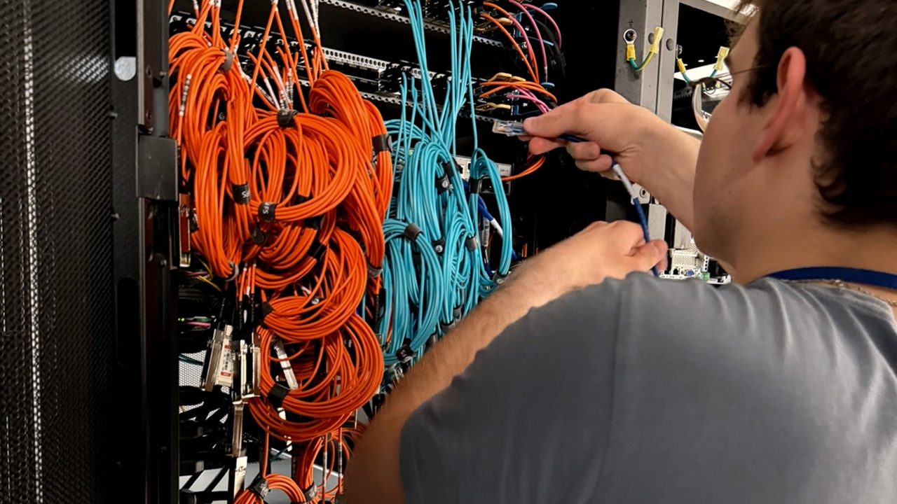 Technician connecting network cables inside a server rack for Boosteroid infrastructure at DC2SCALE.